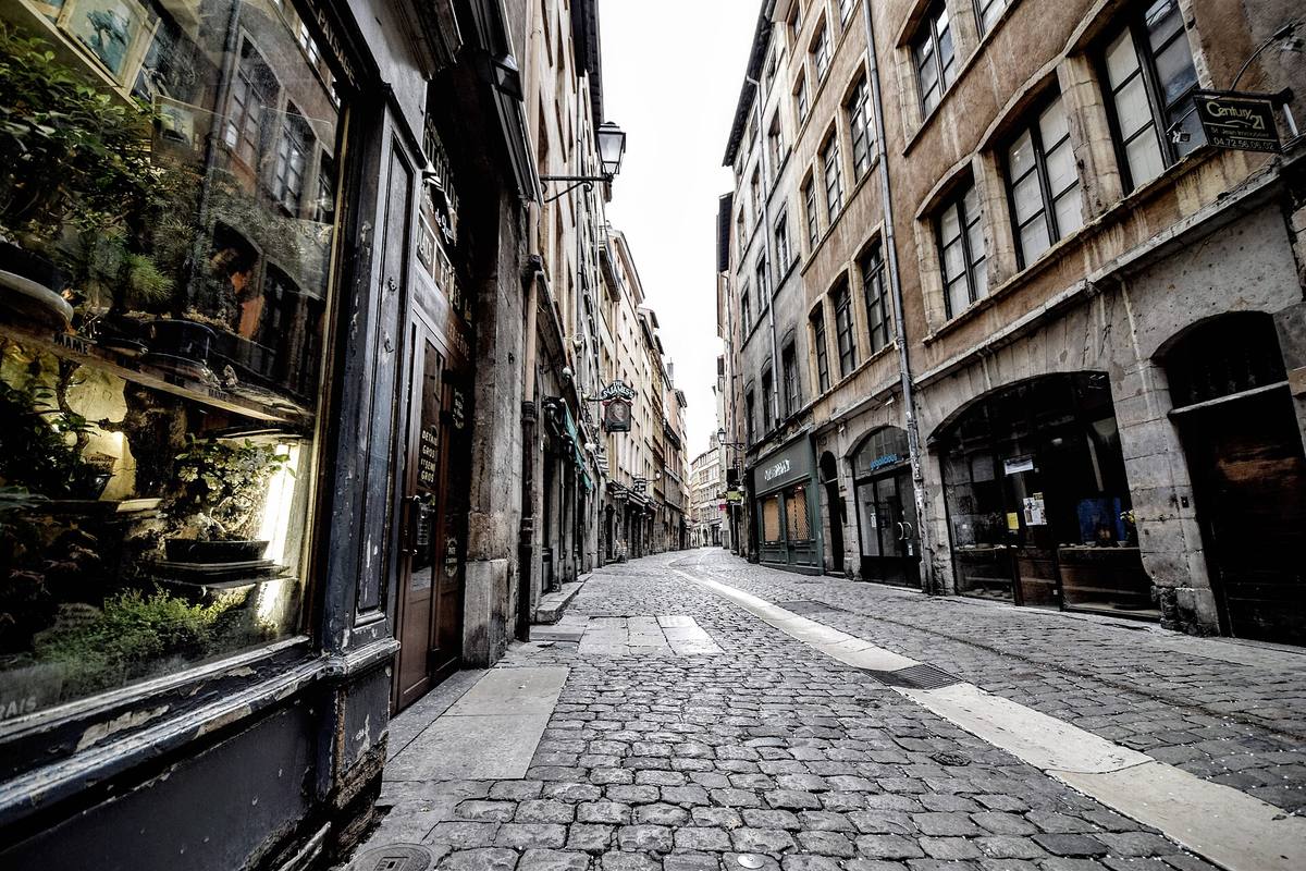Une rue pavée du Vieux-Lyon bordée de façades anciennes et de vitrines