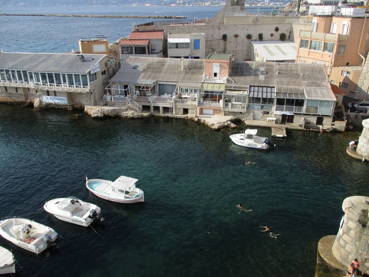 Le petit port du Vallon des Auffes à Marseille, avec ses cabanons et des baigneurs