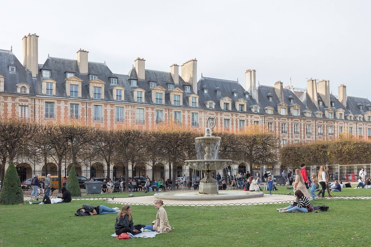 La place des Vosges dans le Marais à Paris, ses pavillons en brique et sa fontaine