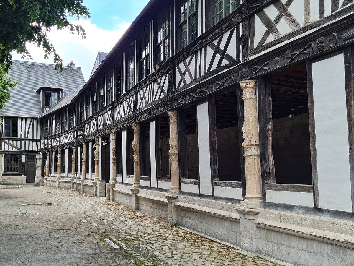 La galerie à pans de bois de l'aître Saint-Maclou à Rouen, avec ses colonnes de pierre sculptées et ses poutres ornées de motifs macabres